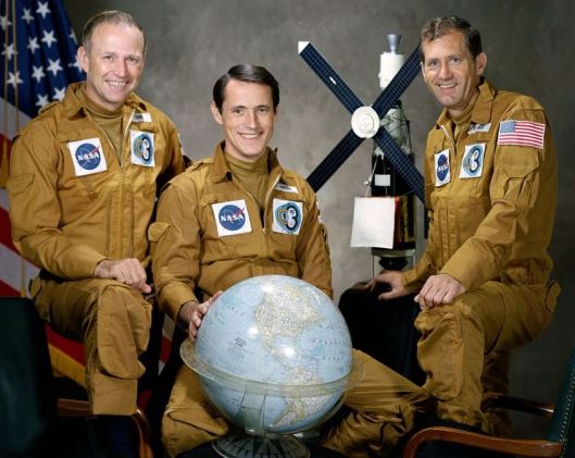 The astronauts on the final Skylab mission. A model of Skylab is in the background